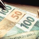 Cédulas de real brasileiro de 100 e 50 reais sobre mesa com caneta, representando a antecipação de crédito judicial de RPV federal